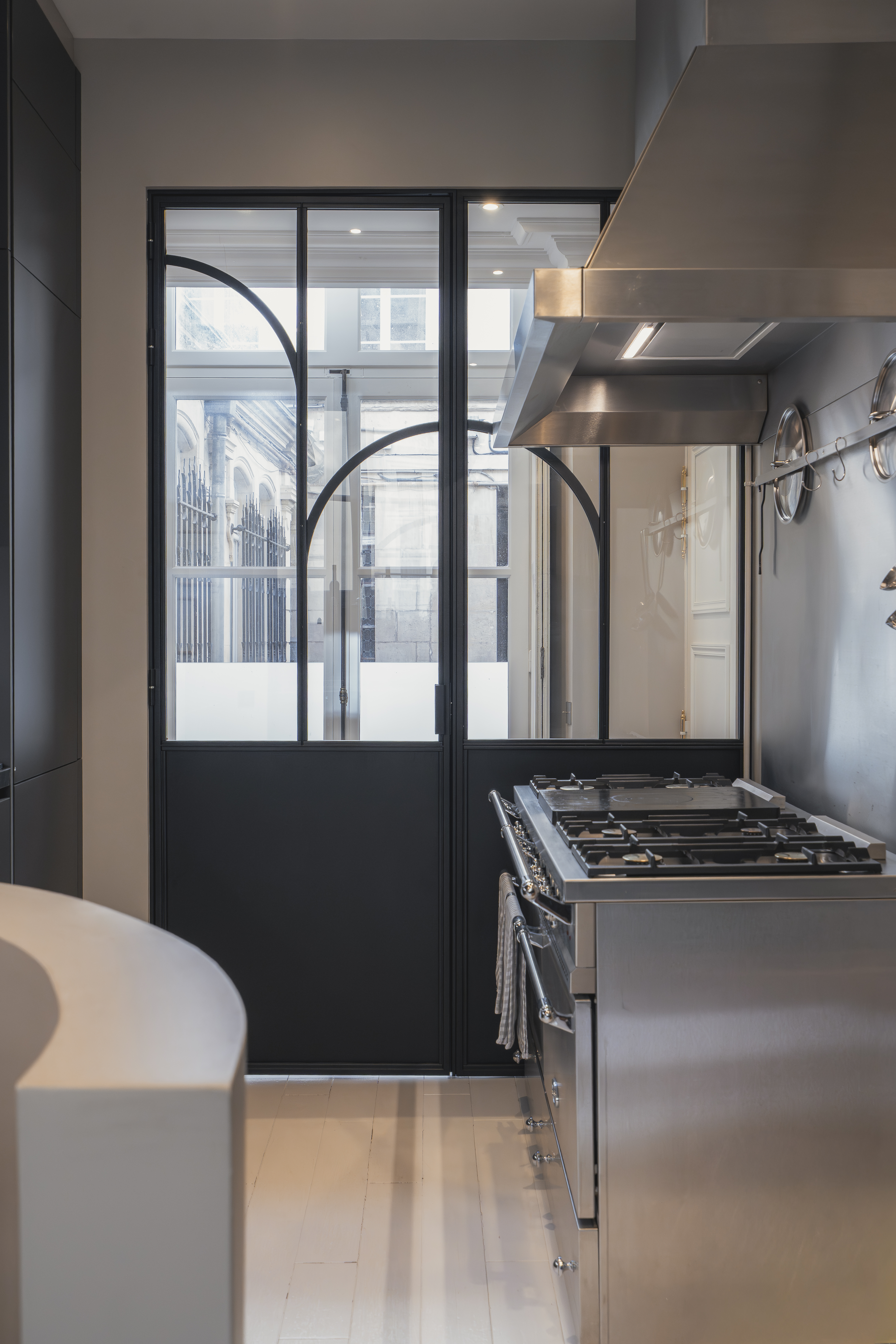 Cuisine avec verrière acier noir Art Déco et piano de cuisson dans un appartement à Deauville