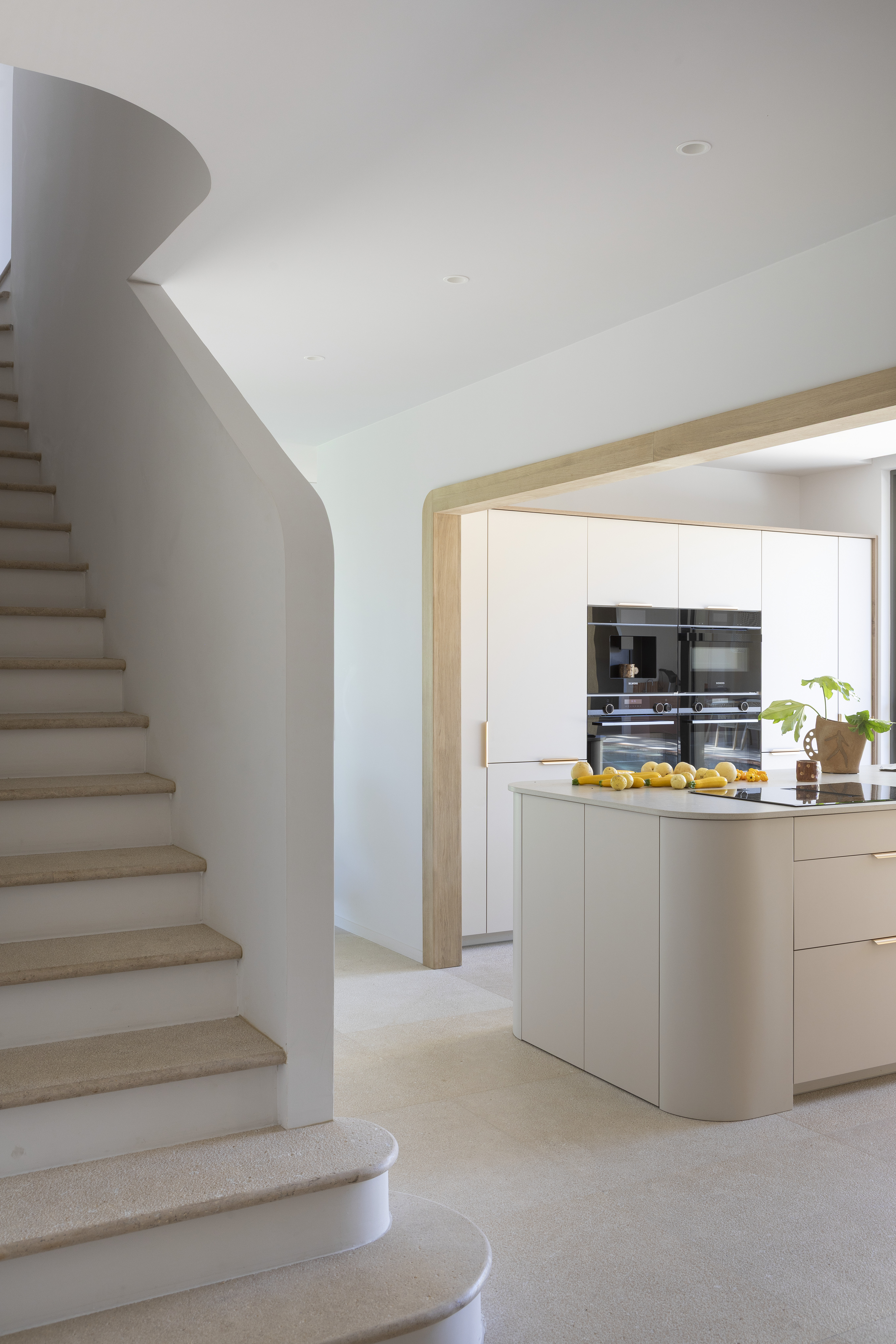 Cuisine-vue-sur-escalier-et-ilot-central-blanc-bois